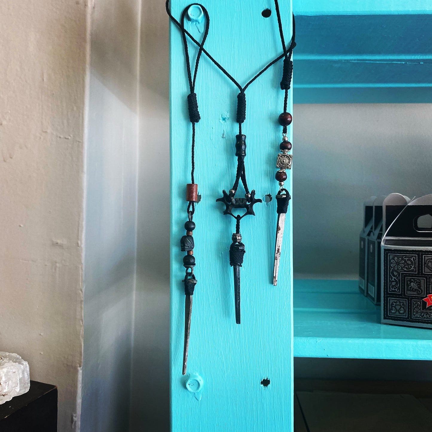 Hanging coffin nail pendulums.